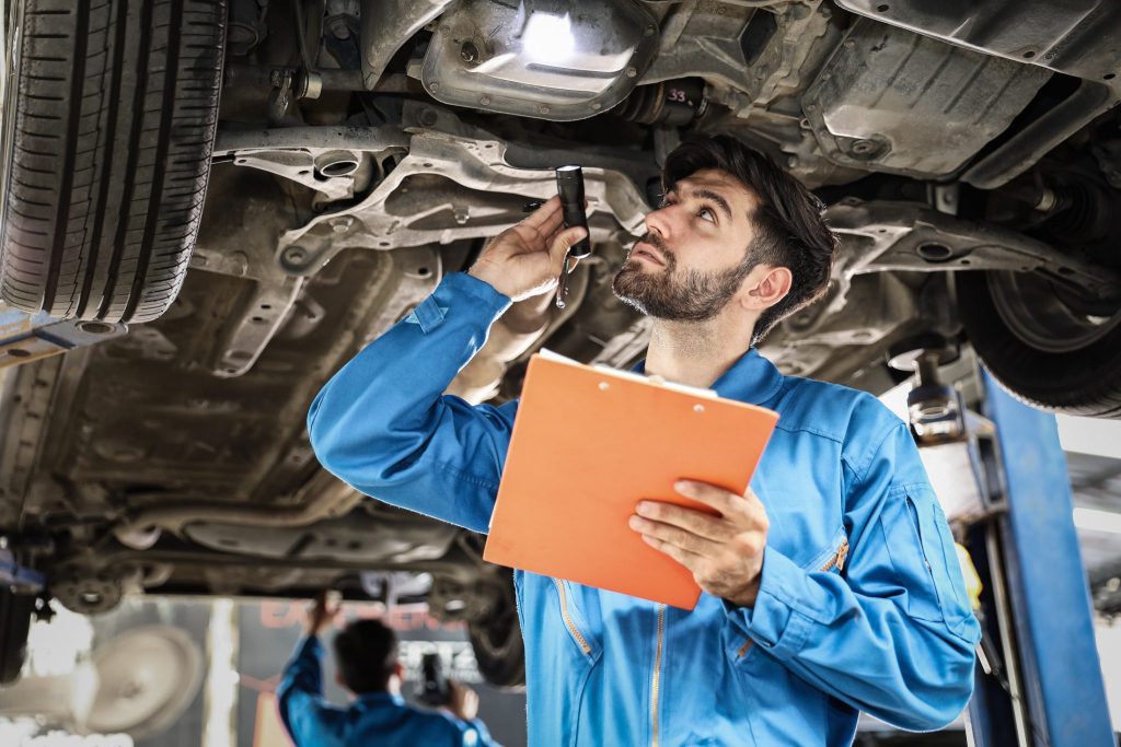 Two mechanics inspect the underneath of a car during an MOT test in Northampton