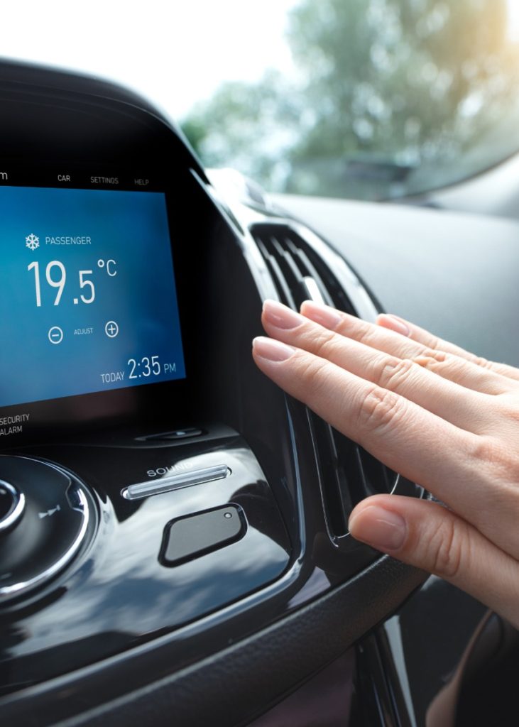 A person holds their hand to their car air conditioning in Northampton to see if it is working. The dashboard says the car temperature is 19.5 degrees Celsius.