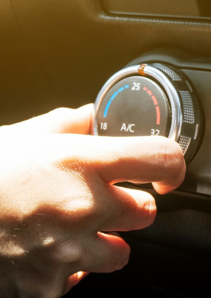Person adjusting the air con in their car after an air con re-gas in Northampton.